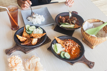 Sambal gami cumi or squid with sambal cooked in earthenware plate against wooden background. Served on wooden table