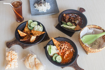 Sambal gami cumi or squid with sambal cooked in earthenware plate against wooden background. Served on wooden table