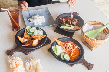 Sambal gami cumi or squid with sambal cooked in earthenware plate against wooden background. Served on wooden table