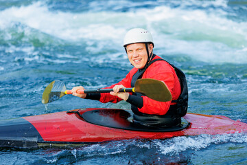 Man in red kayak sails mountain river. Whitewater kayaking, extreme sport rafting