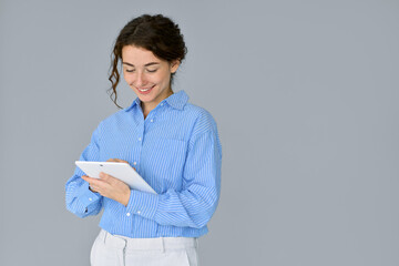 Young smiling professional business woman office worker holding digital tablet, using tab computer standing isolated at gray background advertising online education on smart tech device.