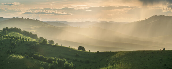 Obraz premium Panoramic view of the spring evening, hills and mountain slopes in sunset light