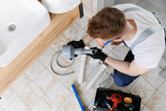 Plumber Man At Work In Bathroom, Fix Repair Service With Pipe Of Sewage, Top View. Concept Install Plumbing