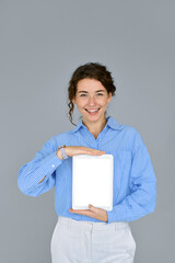 Young smiling business woman model holding digital tablet computer showing blank empty mock up screen display advertising software, website or web service standing isolated on gray background.