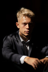 Fototapeta premium A portrait of a blond man in a suit on a black background 