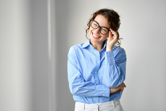 Happy young smiling professional business woman, happy pretty lady manager leader executive wearing glasses looking away, laughing, standing indoors in office space, authentic candid shot.