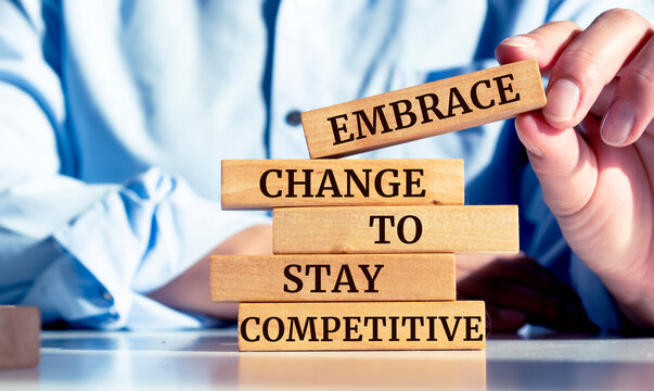 Close up on businessman holding a wooden block with "Embrace change to stay competitive" message