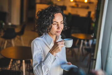Mature woman having cup of coffee at home or office in morning
