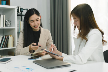 Two professional millennial Asian startup businesspeople are discussing evaluation data in a...