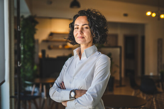 One woman mature caucasian female businesswoman entrepreneur stand at work or home real people copy space wear white shirt curly hair
