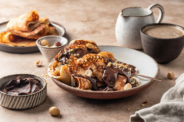 Crepes with chocolate and hazelnuts on beige background. Thin pancakes as delisious breakfast or dessert concept, Pancake day, Maslenitsa