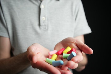 Man holding colored earplugs in his hands