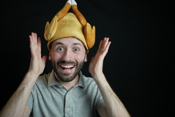 Funny man wearing thanksgiving turkey hat, black background - obrazy, fototapety, plakaty