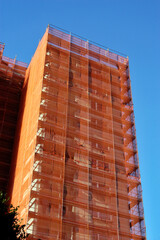 Eingerüstetes Hochhaus mit Bauschutznetz während Renovierungsarbeiten