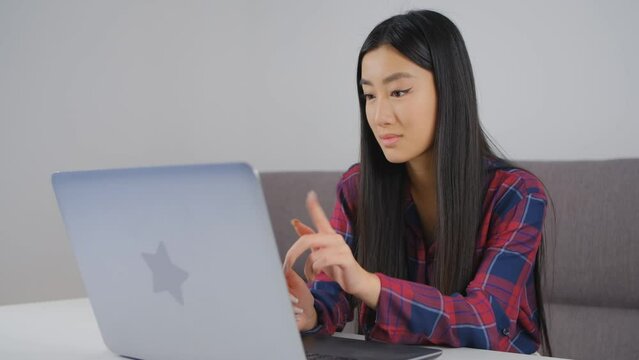 Beautiful Vietnamese girl nodding on a web camera during a video call. Pretty BIPOC female communicating online with a computer