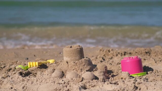 Beach background. Kids plastic toys - buckets, spade and shovel on sand sunny day. Children built sand castle near sea during summer vacation holiday