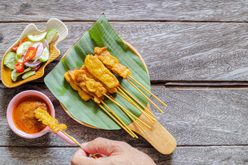 Pork satay grilled pork served with peanut sauce or sweet and sour sauce on Banana leaf  Asian food style on wood table.
