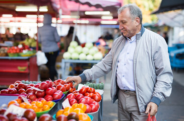 Man choosing tomatoes in greengrocery
