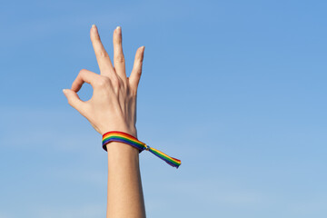 Woman's hand okay gesture with LGTB rainbow bracelet for Pride Day