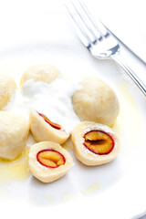 plum dumplings with sour cream, powder sugar and melted butter