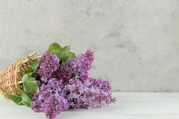 Fototapeta na wymiar Spring bouquet of lilacs in a basket on a light background