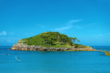 Naklejka premium San Nicolas Island in Lekeitio, Basque Country, Spain. Scenic coastal view with blue Atlantic water, rocky shoreline and lush green island landscape. Popular travel destination on the Bay of Biscay