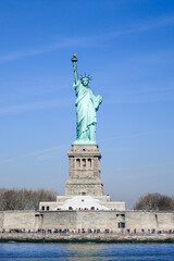 Fototapeta premium Statue of Liberty and base in full sun, clear blue sky. Looking head on at Statue from the Bay.