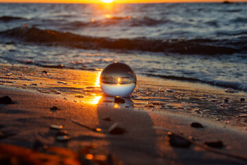 Beach and sea reflected in a sphere lying in the sand in the waves