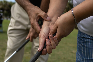 Golf instructor teaching how to a female apprentice to adjust her grip