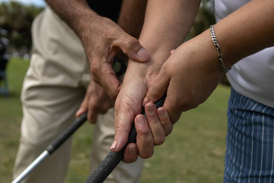 Golf instructor teaching how to a female apprentice to adjust her grip
