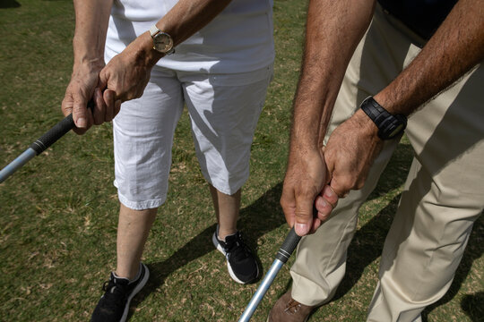 Golf instructor teaching how to a female apprentice to adjust her grip