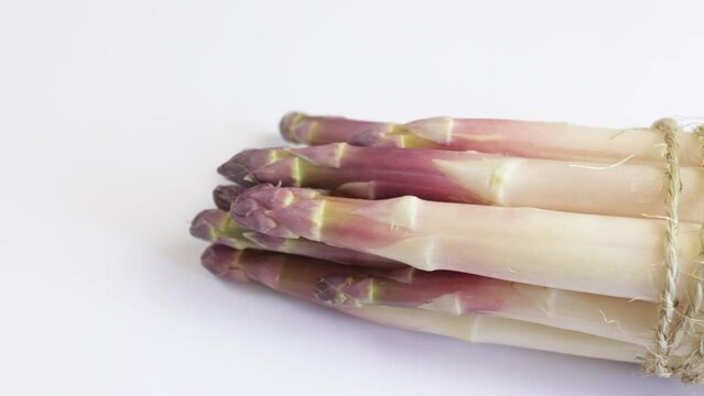 fagot d'asperges violettes, en gros plan, sur un fond blanc