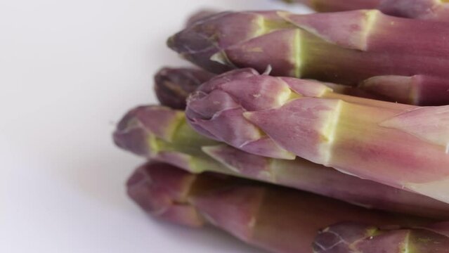 fagot d'asperges violettes, en gros plan, sur un fond blanc