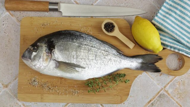  daurade enti&egrave;re, en gros plan, sur une planche &agrave; d&eacute;couper