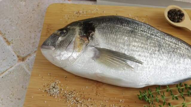  daurade enti&egrave;re, en gros plan, sur une planche &agrave; d&eacute;couper