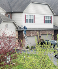 Worker Climbing Ladder to Repair Roof after Storm