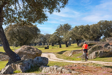 nice senior woman cyling with her electric mountain bike in a stone oak forest of the Extremadura...