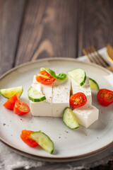 Feta cheese and vegetables - tomatoes and cucumbers in a plate. Light Greek salad