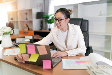 Businesswoman Asian video meeting looking at a screen. paperwork plan around the desk for a lady to search while having an online meeting. female employees have video call and finding document paper