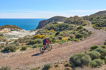 nice senior woman cycling with her electric mountain bike in the volcanic nature park of Cabo de...