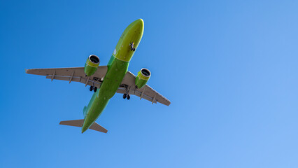 A green and yellow airplane is flying in the sky.