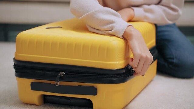 Asian woman packing clothes and closing suitcase for travel in a weekend trip holiday