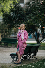 A woman in a pink raincoat in the park.