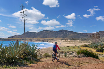nice senior woman cycling with her electric mountain bike in the volcanic nature park of Cabo de...
