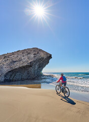 nice senior woman cycling with her electric mountain bike in the volcanic nature park of Cabo de Gata, Costa del Sol, Andalusia, Spain