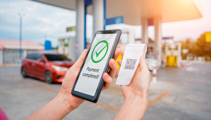 Woman using contactless payment by mobile phone with QR code at car filling station