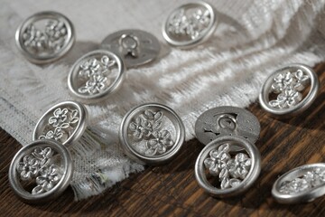 Sewing accessories. Metal buttons with an ear. Buttons are scattered on the gray fabric. Production of women's clothing in a sewing studio.