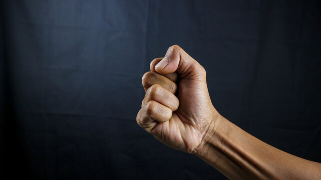 Counting, aggression, brave concept. Black male fist, clenched hand, strong male man raised fist power, protest, fist ready to fight isolated on black background. 