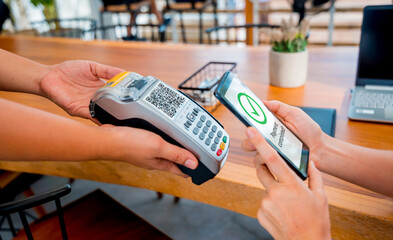 Woman using contactless payment by mobile phone with QR code at cafe