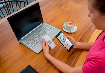Woman using contactless payment by mobile phone with QR code at cafe